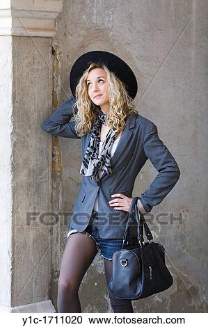 Stock Image - Attractive young woman in Black with a hat. Fotosearch