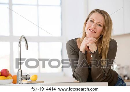 Picture - Attractive young woman in her kitchen. Fotosearch