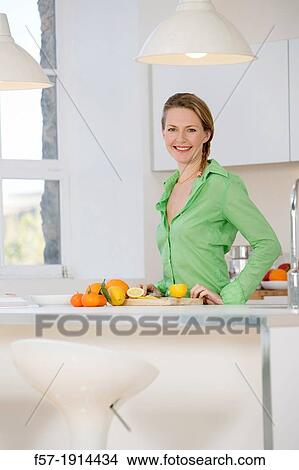 Attractive young woman in her kitchen cutting citrus fruits View Large Photo Image Picture - Attractive young woman in her kitchen cutting citrus fruits. Fotosearch