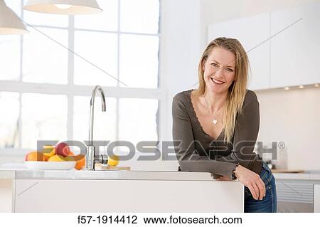 Attractive young woman in her kitchen View Large Photo Image Stock Image - Attractive young woman in her kitchen. Fotosearch