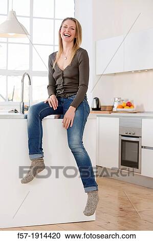 Stock Image - Attractive young woman in her kitchen. Fotosearch