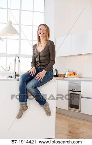 Stock Image - Attractive young woman in her kitchen. Fotosearch