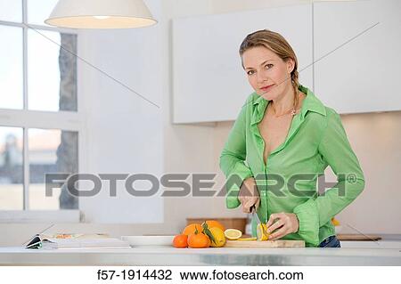 Attractive young woman in her kitchen cutting citrus fruits View Large Photo Image Stock Image - Attractive young woman in her kitchen cutting citrus fruits. Fotosearch