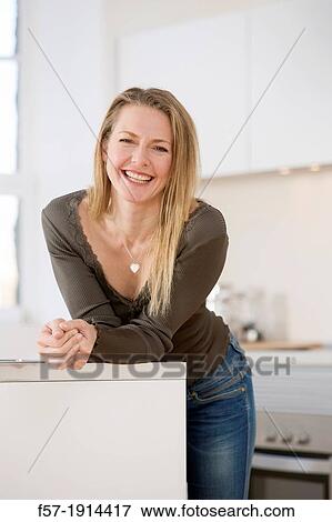 Stock Photo - Attractive young woman in her kitchen. Fotosearch