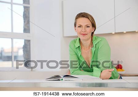 Attractive young woman in her kitchen reading a cookbook View Large Photo Image Stock Photo - Attractive young woman in her kitchen reading a cookbook. Fotosearch