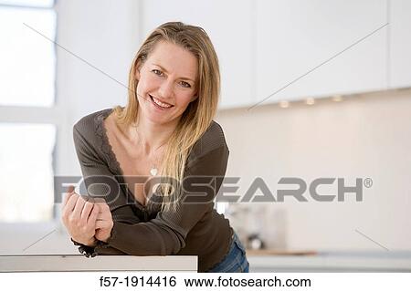 Stock Photograph - Attractive young woman in her kitchen. Fotosearch