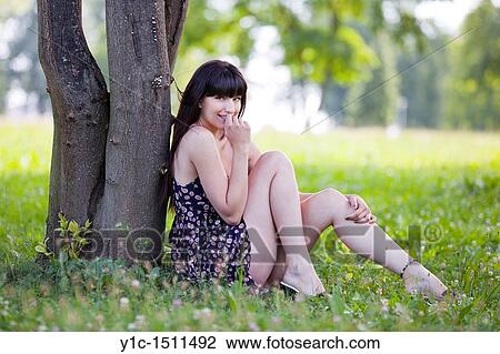 Stock Image - Attractive young woman in the woods is shy. Fotosearch
