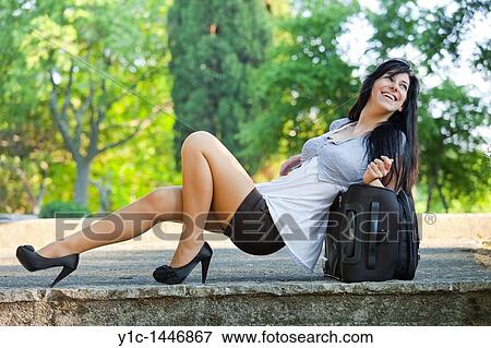 Attractive young woman is almost lying down on a travel suitcase View Large Photo Image Stock Photo - Attractive young woman is almost lying down on a travel suitcase. Fotosearch