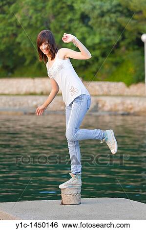 Stock Photograph - Attractive young woman is balancing on one leg. Fotosearch