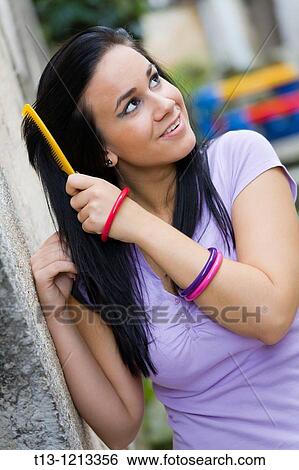 Attractive young woman is brushing hair View Large Photo Image Stock Photograph - Attractive young woman is brushing hair. Fotosearch