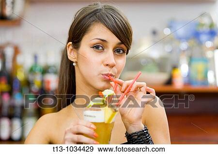 Attractive young woman is drinking a cocktail View Large Photo Image Stock Photo - Attractive young woman is drinking a cocktail. Fotosearch