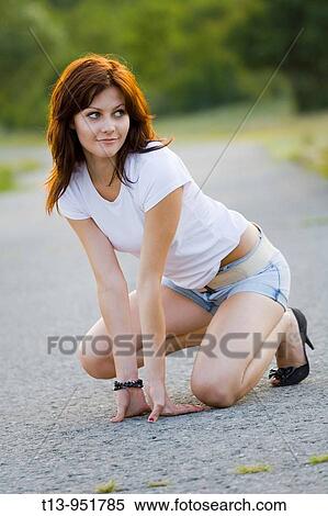 Attractive young woman is kneeling on the road View Large Photo Image Stock Photography - Attractive young woman is kneeling on the road. Fotosearch