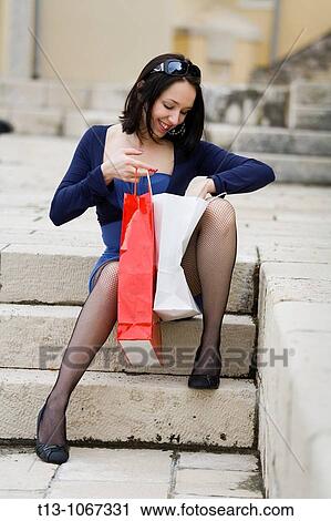 Attractive young woman is looking into her shopping bags View Large Photo Image Stock Image - Attractive young woman is looking into her shopping bags. Fotosearch