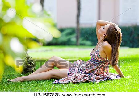 Attractive young woman is lying on a grass in the park View Large Photo Image Stock Photo - Attractive young woman is lying on a grass in the park. Fotosearch