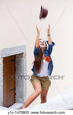 Stock Image - Attractive young woman is playing with a hat. Fotosearch