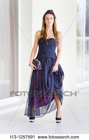 Stock Image - Attractive young woman is posing in formal long dress. Fotosearch