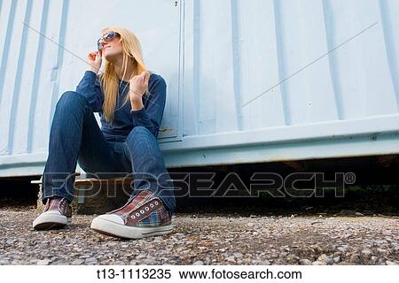 Attractive young woman is sitting by the light Blue wall View Large Photo Image Stock Photography - Attractive young woman is sitting by the light Blue wall. Fotosearch