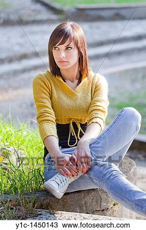 Stock Image - Attractive young woman is sitting in the park. Fotosearch