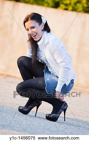 Attractive young woman is squatting and laughing on the street View Large Photo Image Stock Photography - Attractive young woman is squatting and laughing on the street. Fotosearch