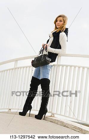 Attractive young woman is standing by the metal fence View Large Photo Image Stock Image - Attractive young woman is standing by the metal fence. Fotosearch