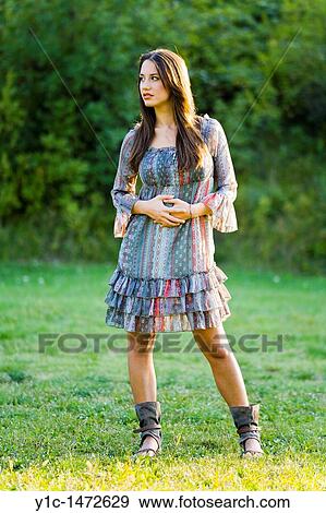 Attractive young woman is standing on a grass View Large Photo Image Stock Photo - Attractive young woman is standing on a grass. Fotosearch