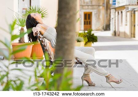 Stock Image - Attractive young woman is stretching on the wooden bench. Fotosearch