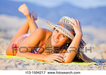 Stock Photo - Attractive young woman lying on the beach. Fotosearch