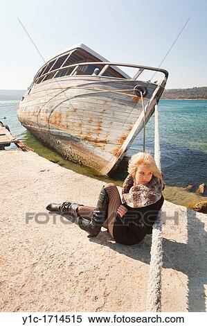 Stock Photography - Attractive young woman next to a big and listing wooden boat. Fotosearch