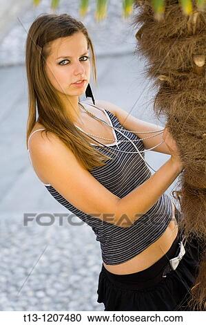 Attractive young woman next to a palm View Large Photo Image Stock Image - Attractive young woman next to a palm. Fotosearch