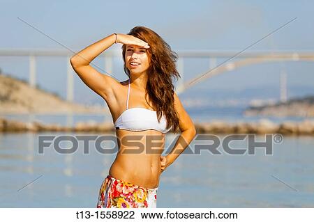 Stock Image - Attractive young woman on the beach is looking at a distance. Fotosearch