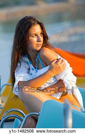 Attractive young woman on the beach is enjoying a warm sunset light View Large Photo Image Stock Photo - Attractive young woman on the beach is enjoying a warm sunset light. Fotosearch