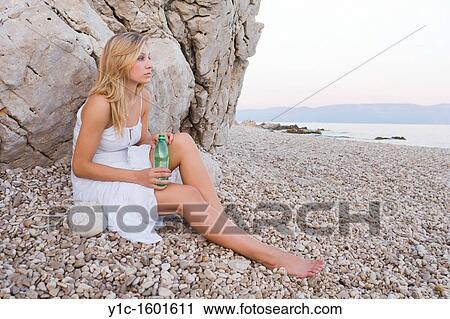 Stock Image - Attractive young woman on the beach with a bottle of drinking water in hand. Fotosearch