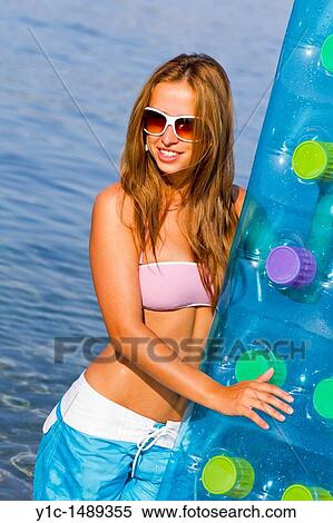 Stock Photography - Attractive young woman on the beach with an inflatable matress in hand. Fotosearch