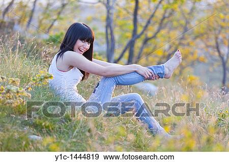 Stock Photo - Attractive young woman playful in the grass. Fotosearch