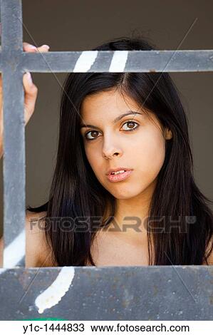 Stock Image - Attractive young woman portrait framed behind a metal frame. Fotosearch