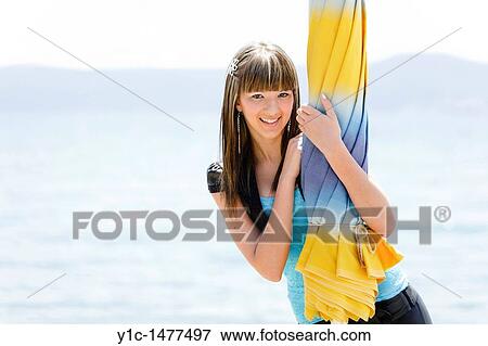Attractive young woman posing behind a closed beach parasol View Large Photo Image Stock Photo - Attractive young woman posing behind a closed beach parasol. Fotosearch
