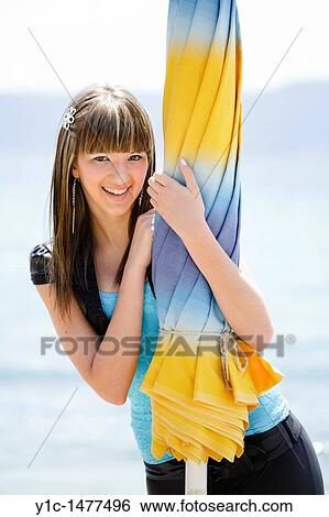 Attractive young woman posing behind a closed beach parasol View Large Photo Image Stock Photograph - Attractive young woman posing behind a closed beach parasol. Fotosearch
