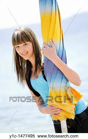 Stock Photography - Attractive young woman posing behind a closed beach parasol. Fotosearch
