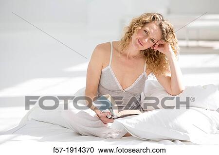 Attractive young woman reading in bed View Large Photo Image Stock Image - Attractive young woman reading in bed. Fotosearch
