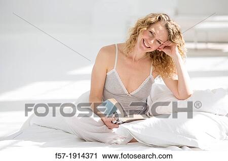 Attractive young woman reading in bed View Large Photo Image Stock Image - Attractive young woman reading in bed. Fotosearch