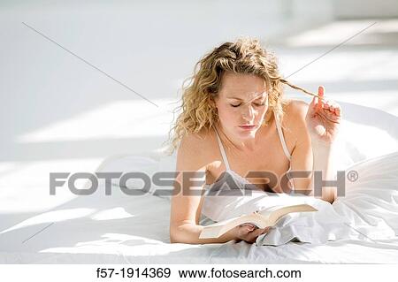 Attractive young woman reading in bed View Large Photo Image Stock Photo - Attractive young woman reading in bed. Fotosearch