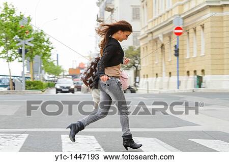 Stock Image - Attractive young woman running on the street. Fotosearch