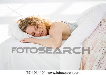 Picture - Attractive young woman sleeping in her bed. Fotosearch