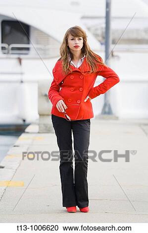 Stock Image - Attractive young woman standing dressed in Red. Fotosearch