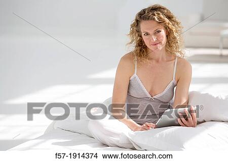 Attractive young woman using her tablet computer in bed View Large Photo Image Picture - Attractive young woman using her tablet computer in bed. Fotosearch