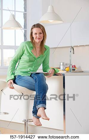 Attractive young woman using her tablet computer in her kitchen View Large Photo Image Stock Photo - Attractive young woman using her tablet computer in her kitchen. Fotosearch