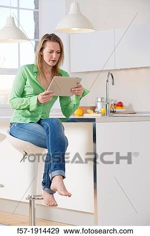 Attractive young woman using her tablet computer in her kitchen View Large Photo Image Stock Photo - Attractive young woman using her tablet computer in her kitchen. Fotosearch