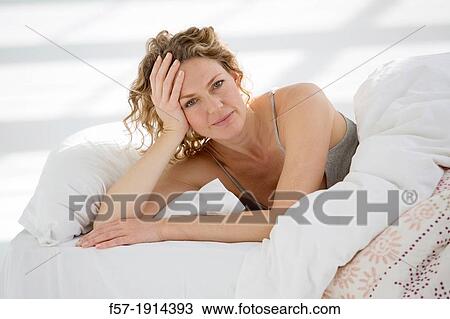 Stock Image - Attractive young woman waking up in her bed. Fotosearch