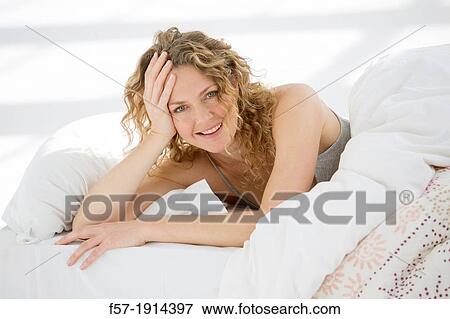 Stock Photo - Attractive young woman waking up in her bed. Fotosearch