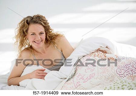 Stock Photo - Attractive young woman waking up in her bed. Fotosearch
